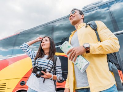 woman-holding-digital-camera-and-looking-away-with-mixed-race-man-holding-map-near-travel-bus-1536x1025
